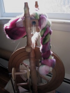 handpainted fiber hanging on upright spinning wheel