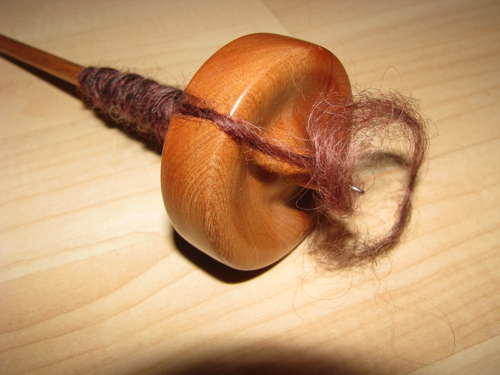 reddish brown wool on a hand spindle