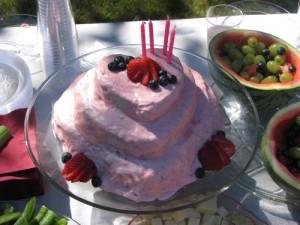 three layer heart shaped pink icing chocolate cake with strawberries and blueberries